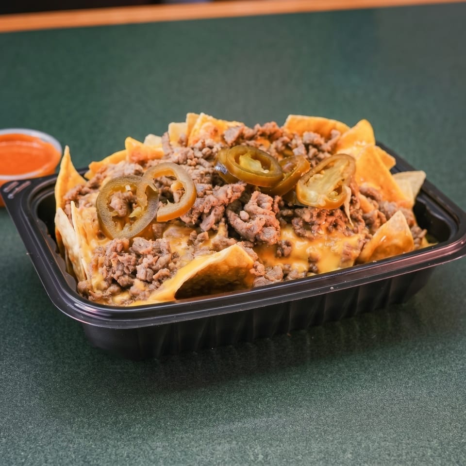 Nachos with ground beef, melted cheese, and sliced jalapeños in a black takeout container.